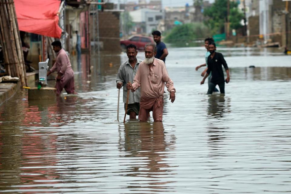 PHOTO: Residents wade across a flooded street after heavy monsoon rains in Karachi, Pakistan, July 26, 2022.  (Rizwan Tabassum/AFP via Getty Images)