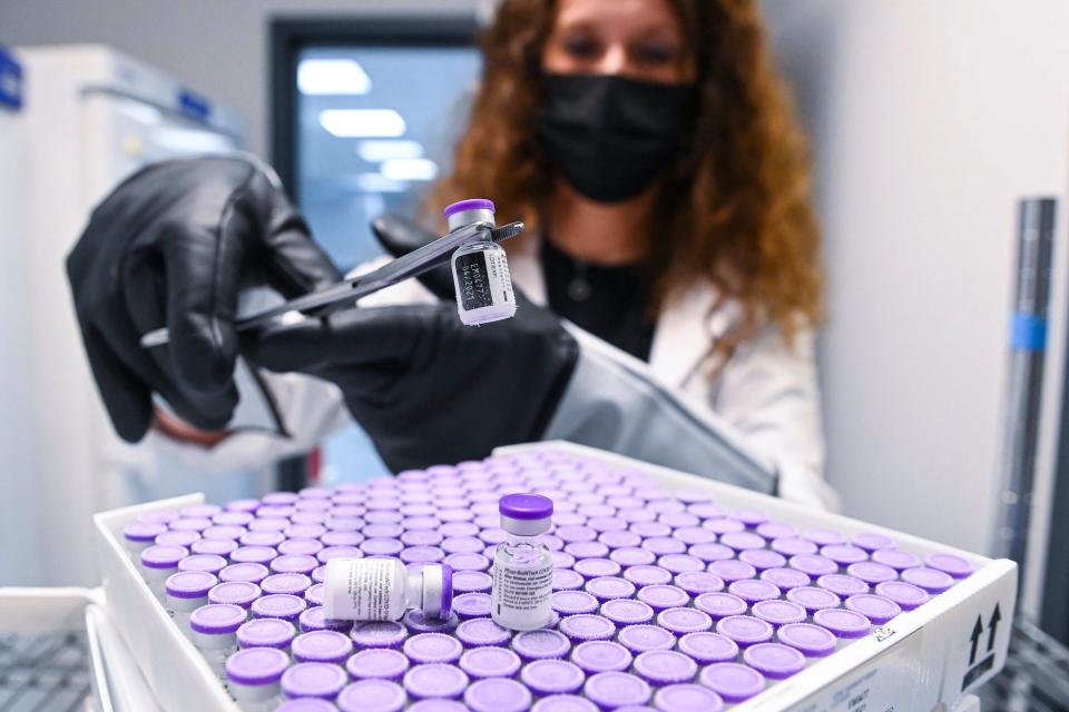 A woman picks up a Pfizer mRNA COVID-19 vaccine dose