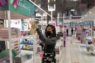 Tamia Prescott sanitizes a cosmetic display Thursday, Nov. 19, 2020, at an Ulta beauty store on Chicago's Magnificent Mile. (AP Photo/Charles Rex Arbogast)