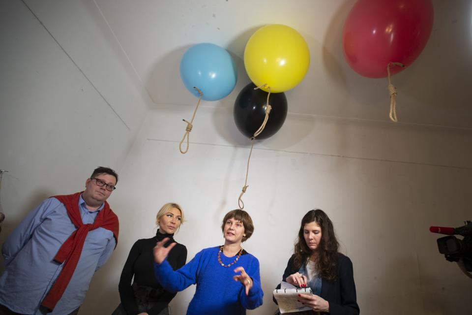 In this photo taken on Sunday, Oct. 27, 2019, Austrian artist Michele Pagel speaks in front of her work which shows rope nooses suspended from balloons bringing an issue often dismissed to the periphery of Russian society back to its center of attention, as Simon Mraz, Austria's cultural attache to Russia and director of the Austrian Cultural Forum in Russia, stands at left at an opening ceremony of her exhibition in Moscow, Russia. Moscow’s suburbs are the focus of a major international art exhibition that has just opened in the Russian capital. The exhibit uses contemporary art to explore the many hidden facets of life beyond the Russian capital’s nucleus. Austrian cultural attache says the ‘real’ Moscow where most of the city’s 12.6 million people live, is outside the center. (AP Photo/Alexander Zemlianichenko)