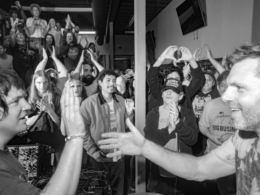 A group of people applauding musicians who are about to hug and high five at a laundromat