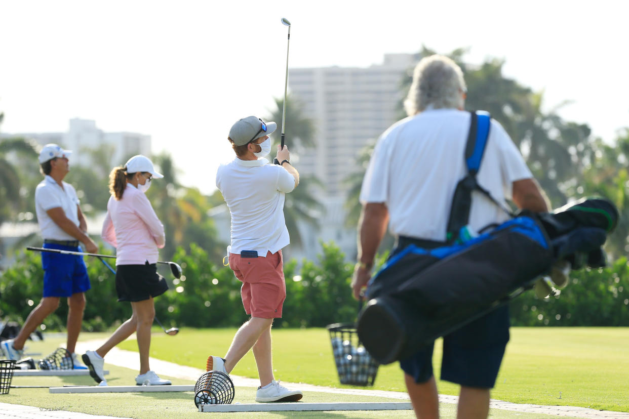 Players wearing face masks warm up on the range at the Miami Beach Golf Club on April 29, 2020 in Miami Beach, Florida.  The city of Miami Beach partially reopened parks and facilities including golf courses, tennis courts and marinas as it begins easing restrictions made due to the COVID-19 pandemic. (Cliff Hawkins/Getty Images)