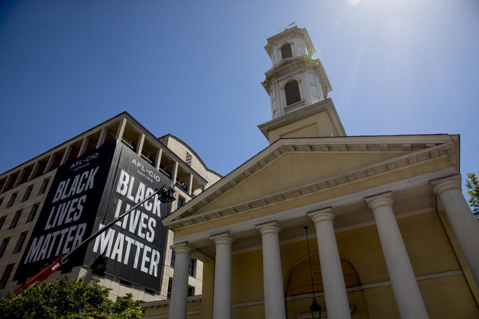 FILE - This Friday, June 12, 2020 file photo shows St. John's Episcopal Church next to a large "Black Lives Matter" banner on the AFL-CIO building near the White House in Washington. In 2020, mainline Protestant denominations, including the Episcopal, United Methodist and Presbyterian-USA churches, are now deeply engaged in campaigns against racism and voter suppression. (AP Photo/Andrew Harnik)