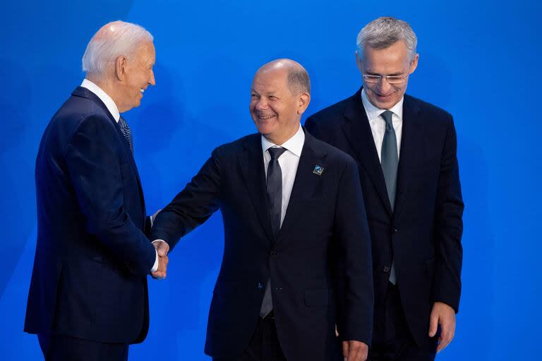 El presidente estadounidense Joe Biden y el secretario general de la OTAN Jens Stoltenberg saludan al canciller alemán Olaf Scholz (C) en el escenario antes de una foto de grupo durante la cumbre de la OTAN de 2024 el 10 de julio de 2024 en Washington, DC.