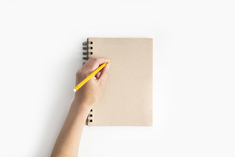 Someone holding a pencil above a notebook