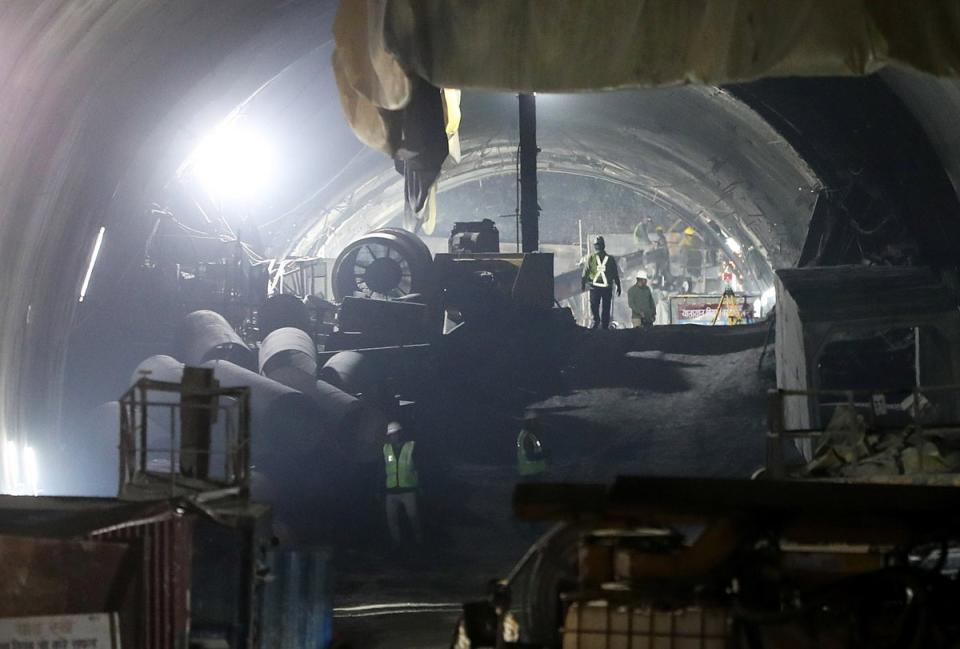 Rescue workers gather among heavy machinery in the tunnel (EPA)