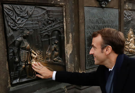 FILE PHOTO: French President Emmanuel Macron touches the bronze dog on the base of the statue of St John of Nepomuk at the medieval Charles Bridge in Prague, the Czech Republic October 27, 2018. REUTERS/David W Cerny