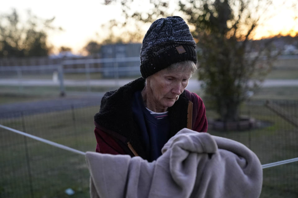 Lou Ann Trahan, who suffers from dementia, takes a blanket off a clothes line to stay warm on Christmas Eve, in the gutted home of her daughter in the aftermath of Hurricane Laura and Hurricane Delta, in Lake Charles, La., Thursday, Dec. 24, 2020. The extended family is living in tents and campers on the property, having all lost their homes to the storms. (AP Photo/Gerald Herbert)