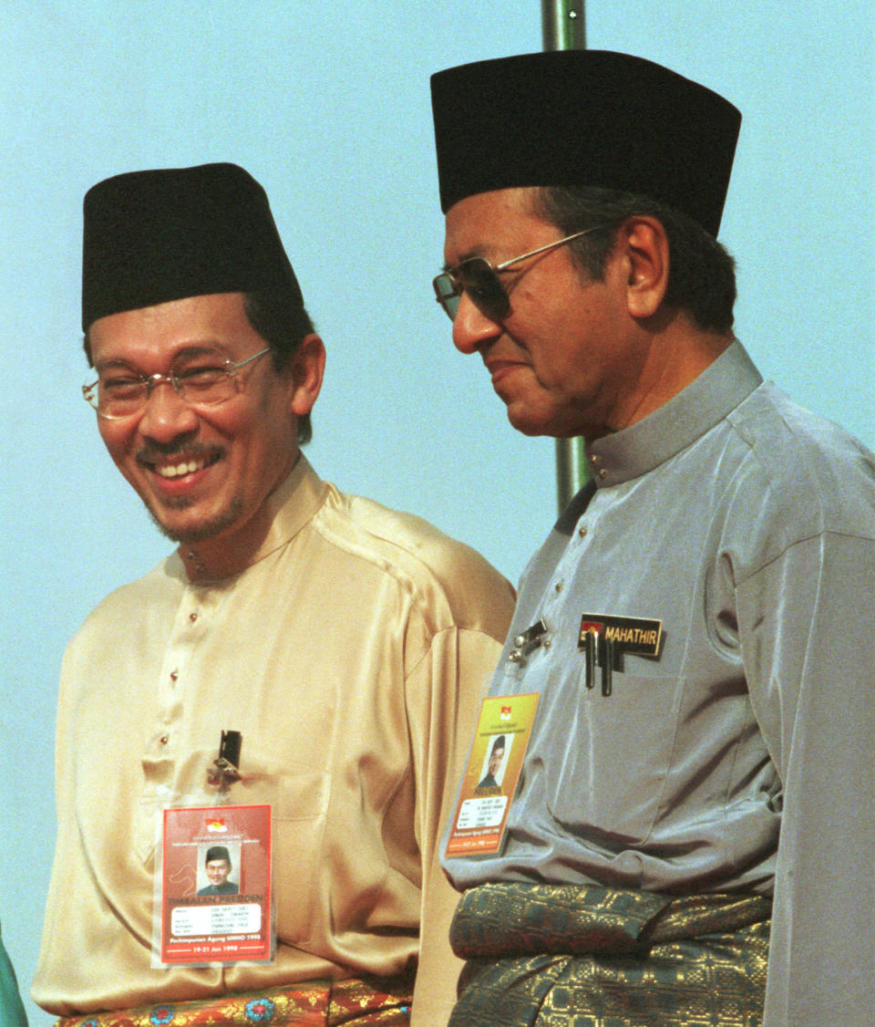 FILE - In this June 20, 1998, file photo, Anwar Ibrahim, left, stand next to Malaysia Prima Minister Mahathir Mohamad during the 1998 UMNO Annual Meeting in Kuala Lumpur. Political tension is building in Malaysia amid talks that Mahathir will pull his party out of the ruling alliance and team up with opposition parties to form a new government in a major political upheaval. It will thwart his named successor Anwar Ibrahim from taking over.(AP Photo/Vincent Thian, File)