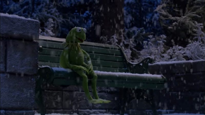 Kermit the Frog sits on a park bench in the snow, slowly freezing to death.