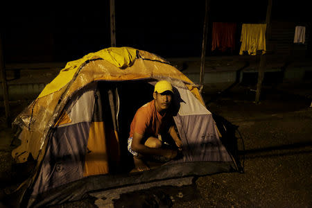 Venezuelan man is pictured at the entrance of his, tent set up along the street, as he waits to show his passport or identity card next day at the Pacaraima border control, Roraima state, Brazil August 8, 2018. Picture taken August 8, 2018. REUTERS/Nacho Doce