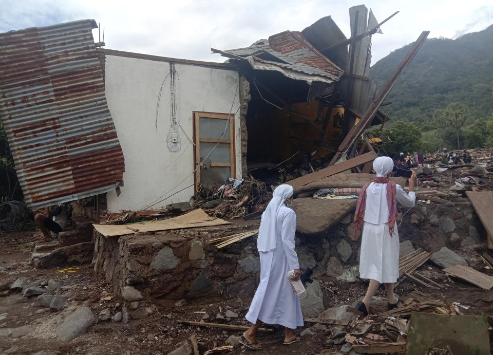 Nuns walk past a damaged house at a flood-affected village in Ile Ape on Lembata Island, East Nusa Tenggara province, Indonesia, Tuesday, April 6, 2021. Rescuers in remote eastern Indonesia were digging through the debris of a landslide Tuesday in search of people believed to be buried in one of several disasters brought on by severe weather in the Southeast Asian nation and neighboring East Timor. (AP Photo/Ricko Wawo)