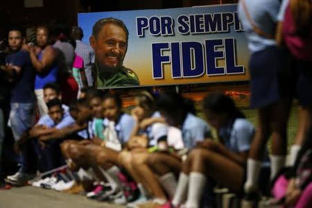 People rest on a sidewalk while waiting for the cortege carrying the ashes of Cuba's former President Fidel Castro to drive toward Santa Ifigenia cemetery in Santiago de Cuba, Cuba, December 4, 2016. REUTERS/Carlos Garcia Rawlins