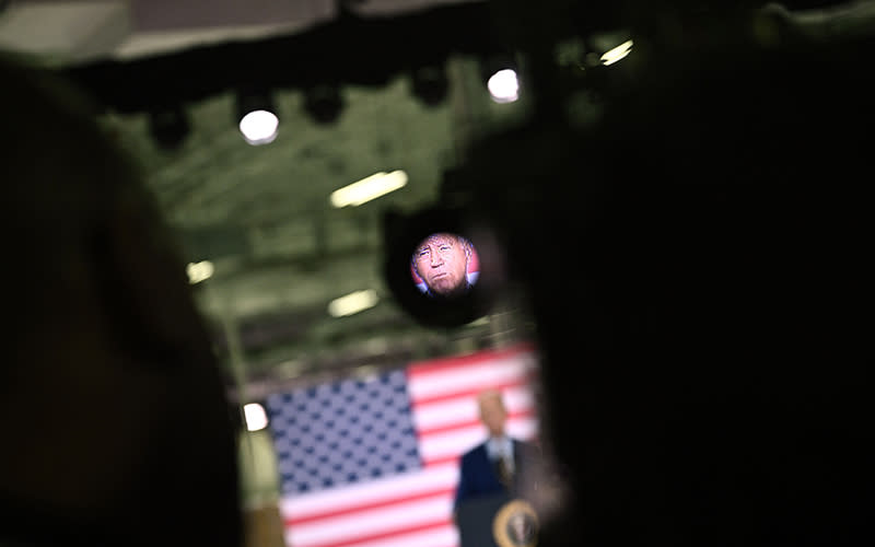 The face of President Biden is shown through a camera lens as he speaks about manufacturing.