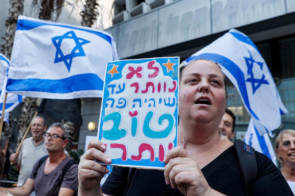 A supporter of Israel's newly formed government "change coalition" holds a placard reading in Hebrew "we won't give up until it's better here!" during a rally in support of the coalition in Tel Aviv, on June 6, 2021.