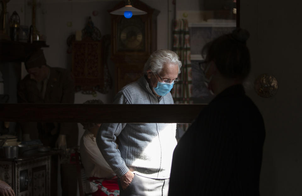 In this photo taken on Tuesday, May 5, 2020, director of the Remember Museum 39-45, Marcel Schmetz, left, stands in a room re-created from his childhood kitchen during World War II as his wife Mathilde looks through a plexiglass window in Thimister-Clermont, Belgium. The couple run a war museum, right where the Battle of the Bulge, Hitler's last stand to change the tide of the war, took place. But what was supposed to be the highlight of the year is now spent in isolation with Mathilde behind closed doors of the museum. (AP Photo/Virginia Mayo)