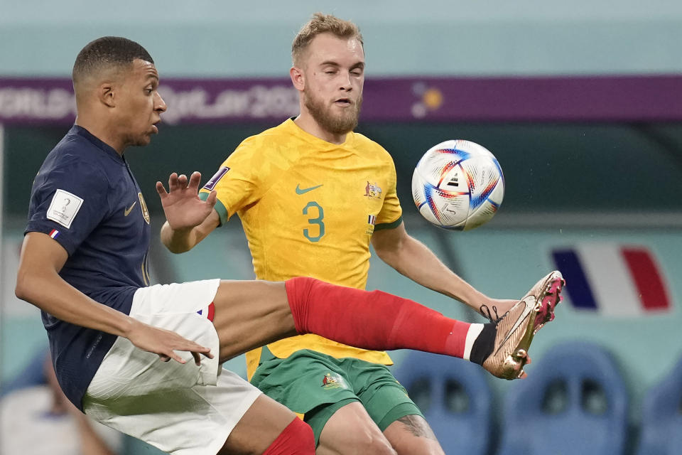 France's Kylian Mbappe, left, and Australia's Nathaniel Atkinson fight for the ball during the World Cup group D soccer match between France and Australia, at the Al Janoub Stadium in Al Wakrah, Qatar, Tuesday, Nov. 22, 2022. (AP Photo/Christophe Ena)