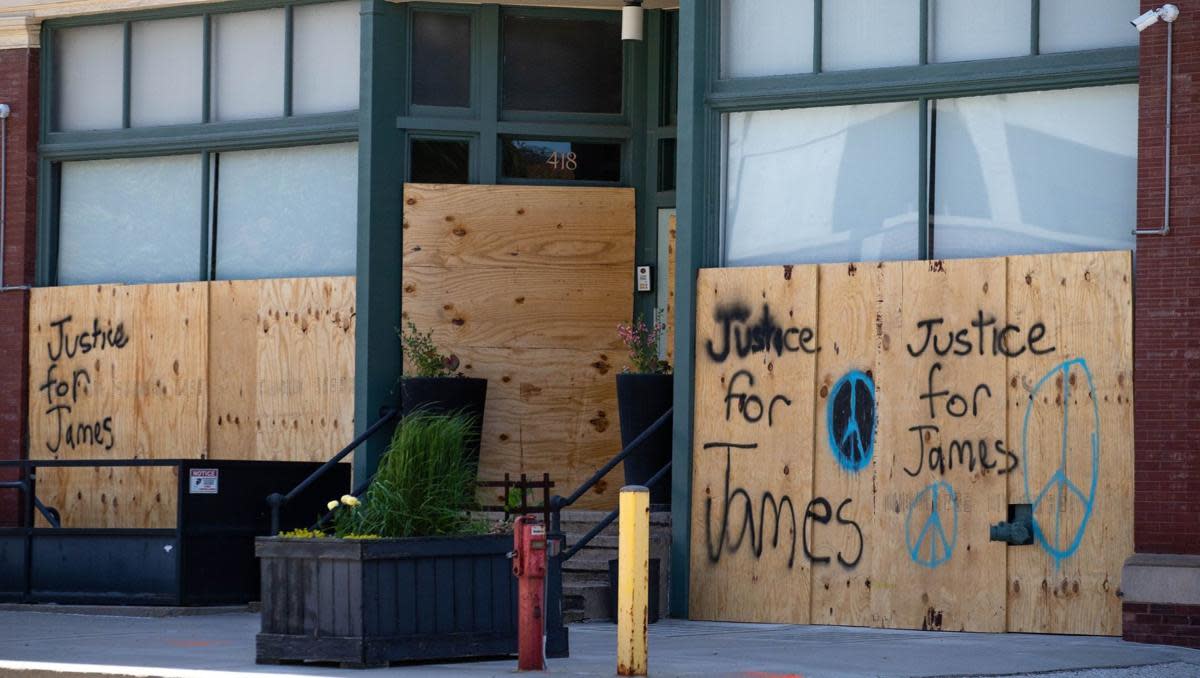 Messages for James Scurlock are spray painted on boarded up windows Monday in downtown Omaha. (Z Long/The World-Herald) 