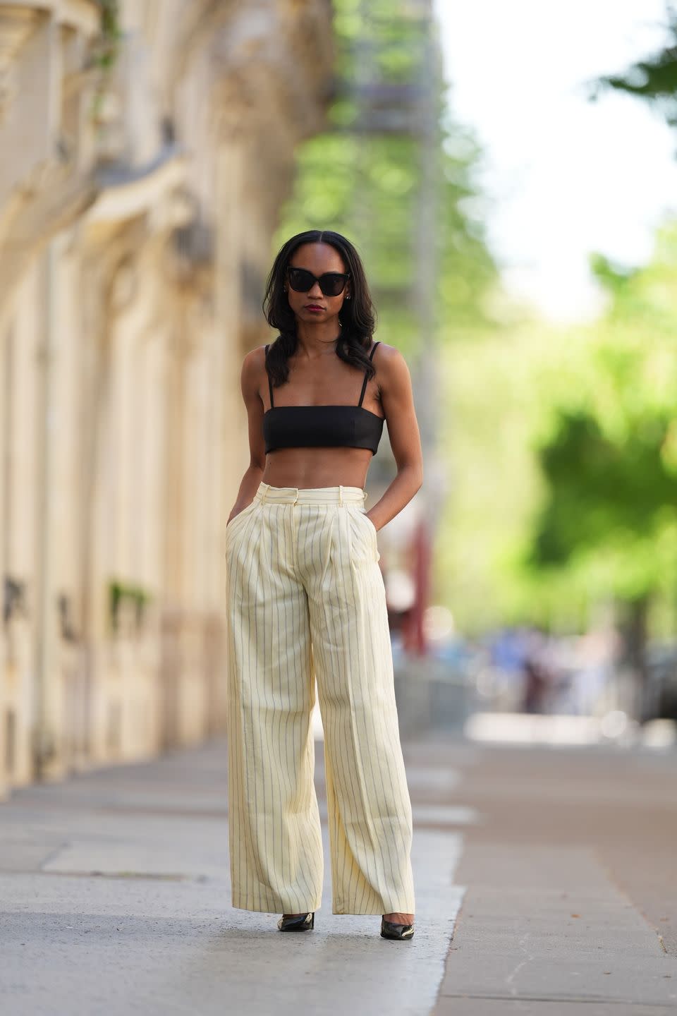 paris, france april 13 emilie joseph wear a full summer linen look from mango, a black crop top bralette with thin straps, beige high waist wide leg linen pants with tennis stripes, pointed shiny shoes, and sunglasses, during a street style fashion photo session, on april 13, 2024 in paris, france photo by edward berthelotgetty images