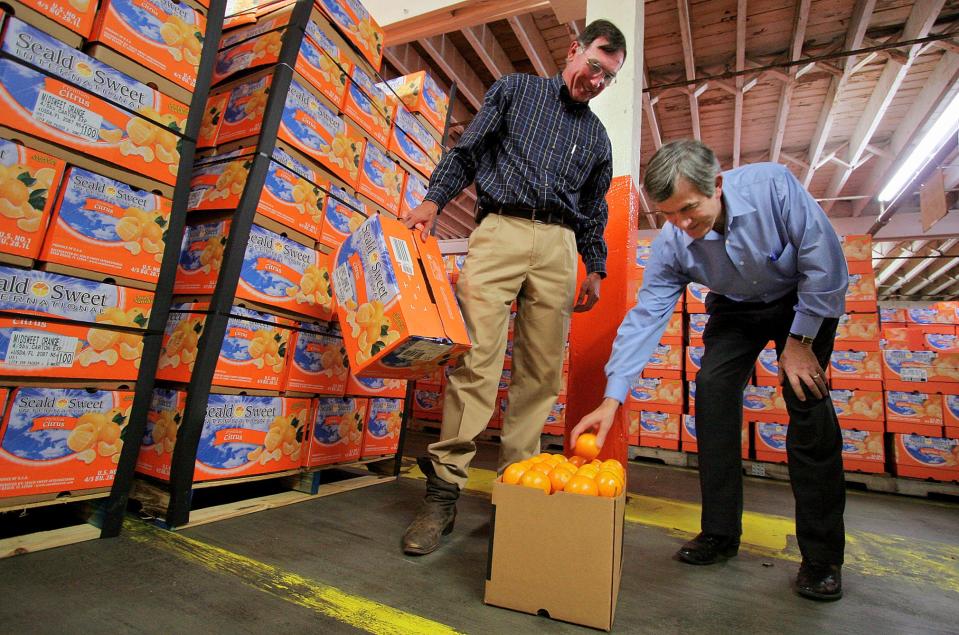 Next to Frank M. Hunt III, then-U.S. Agriculture Secretary Mike Johanns plucks a fresh packed orange at Hunt Bros. packinghouse in Lake Wales in 2006. Hunt announced to employees in April that the packinghouse will close after this season.