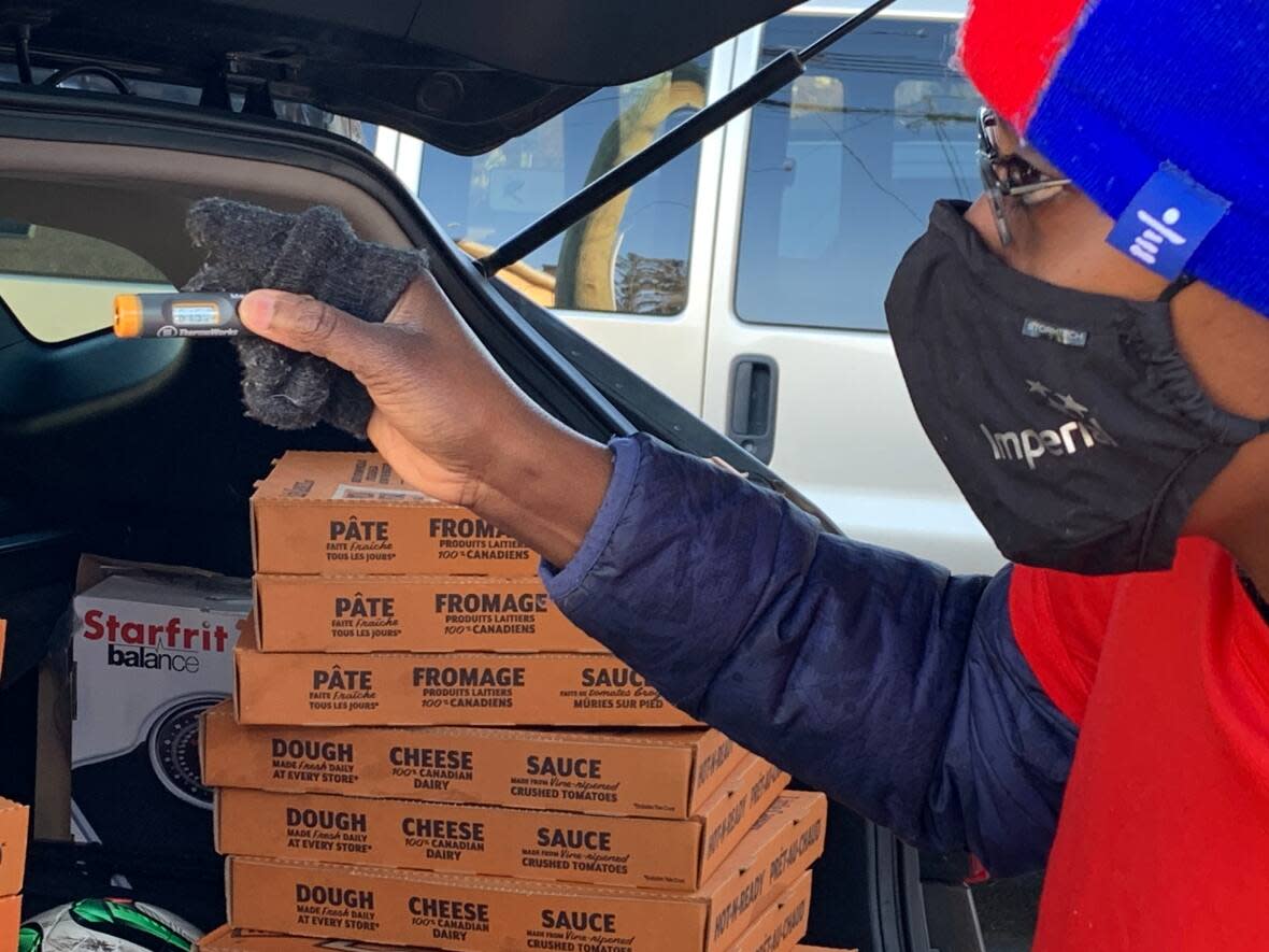 Leftovers volunteer Toks Bakinson checks to ensure unsold pizzas were stored at a cold enough temperature before driving them to a youth drop-in centre. (Elise Stolte/CBC - image credit)