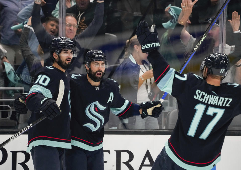 Seattle Kraken center Matty Beniers (10) celebrates his goal against the Dallas Stars with teammates Jordan Eberle (7) and Jaden Schwartz (17) during the third period of Game 6 of an NHL hockey Stanley Cup second-round playoff serie,s Saturday, May 13, 2023, in Seattle. The Kraken won 6-3. (AP Photo/Lindsey Wasson)