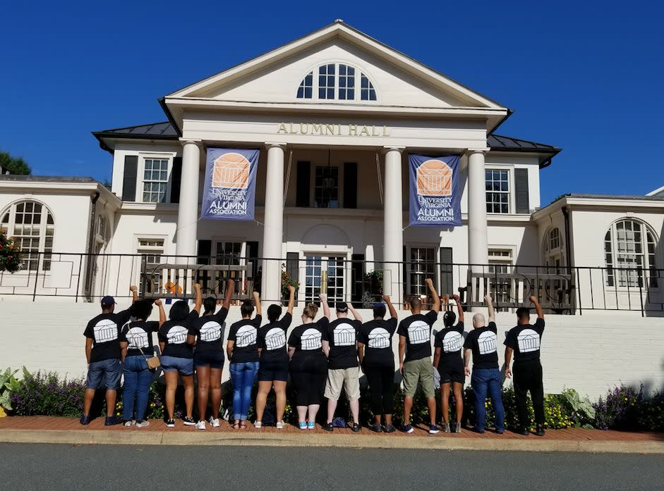 A group of alumni gather on campus and stand in solidarity with their fists raised.&nbsp; (Photo: Quentin Washington)