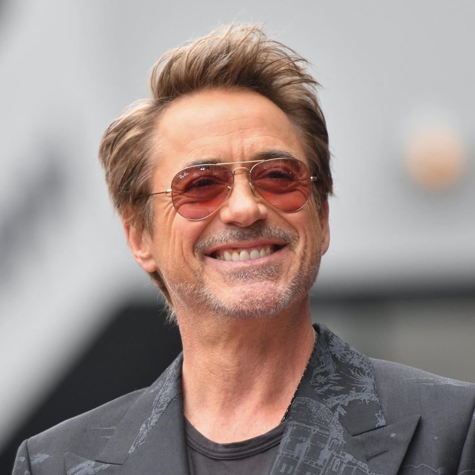 Robert Downey Jr. smiling and wearing sunglasses and a stylish suit jacket at an event