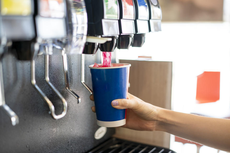 Someone pouring a soda from a soda machine.