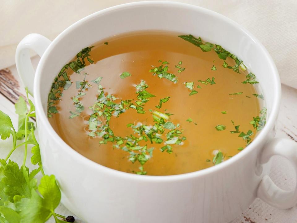 Bone Broth Benefits: Cooked hot bone broth with spices and fresh herbs.