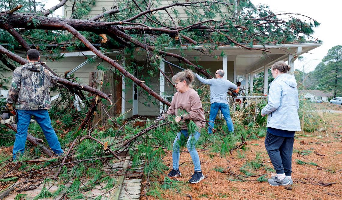 Lisa Stanley, center, and friends start to clean up knocked down trees that hit her son, Griffin’s, home on Buckhorn Road in Garner, N.C., Sunday, Dec. 10, 2023. Lisa said after the storm passed she texted her circle group from Holland’s Church and people showed up to help out. “What an awesome church family” said Stanley.