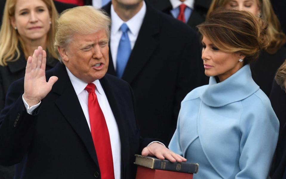 Donald Trump, with his wife Melania Trump, is sworn in as President at the US Capitol in 2017 - AFP