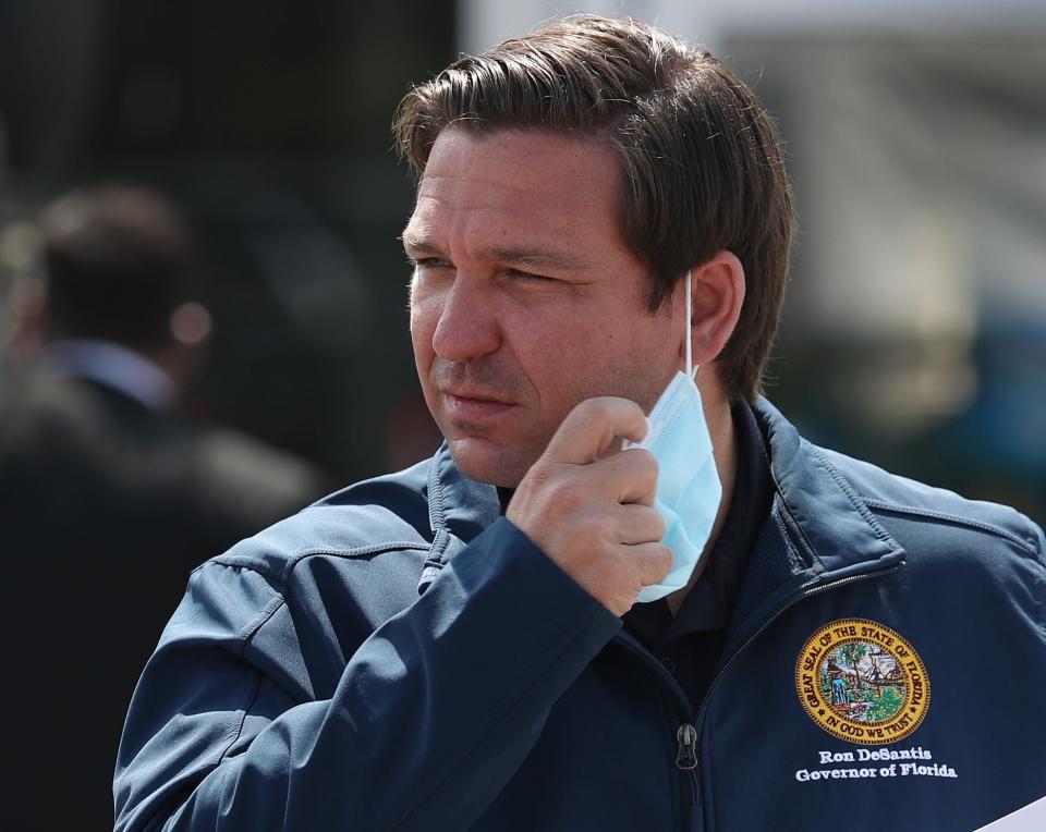 MIAMI GARDENS, FLORIDA - MAY 06: Florida Gov. Ron DeSantis takes his mask off as he prepares to speak during a press conference at the Hard Rock Stadium testing site on May 06, 2020 in Miami Gardens, Florida. Gov. DeSantis announced during the press conference that a COVID-19 antibodies test will be available. The test can show if a person has had the virus in the past without showing symptoms, and therefore may be immune to it. The test will be available to first responders and health care workers first, with the goal of being able to expand testing to the general public.