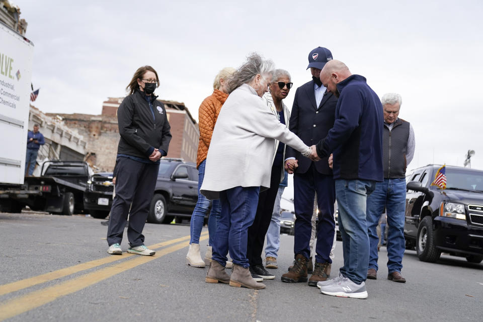 President Joe Biden bows his head as he holds hands Jesse Perry, Graves County Judge Executive and Anne Henning Byfield, Presiding Bishop of the AME Council of Bishops in Mayfield, Ky., Wednesday, Dec. 15, 2021. Mayfield Mayor Kathy Stewart O'Nan is at center left. (AP Photo/Andrew Harnik)