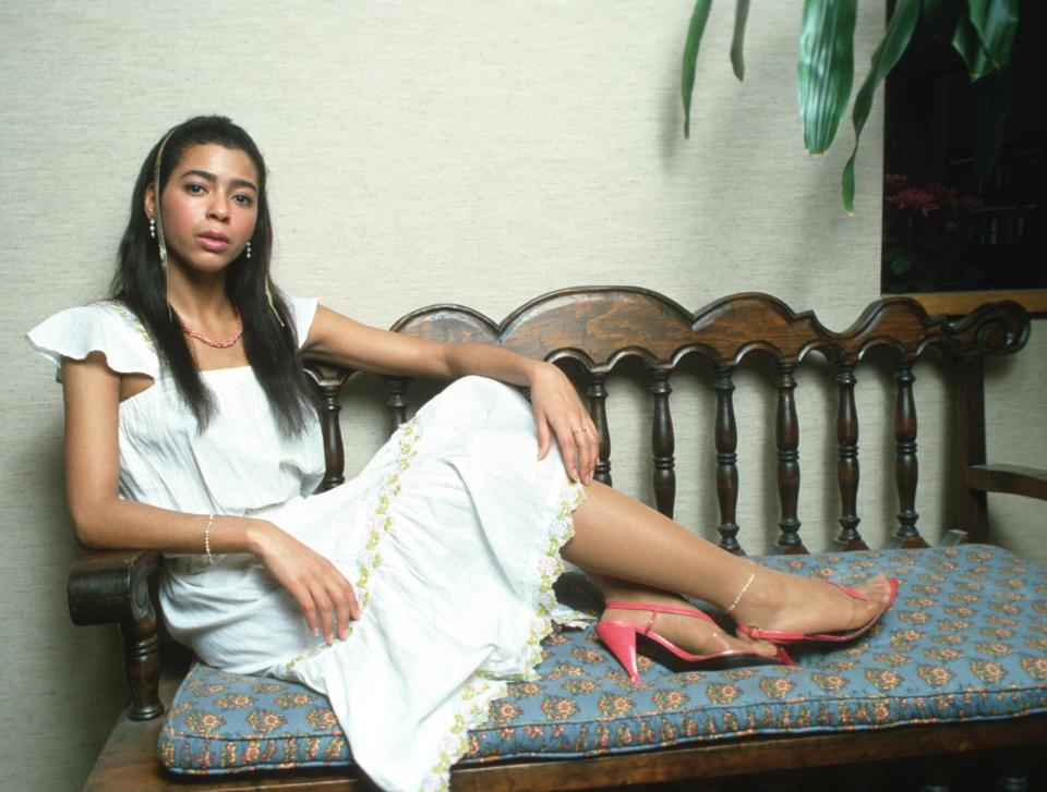 Irene Cara sitting on a chair with a white dress on