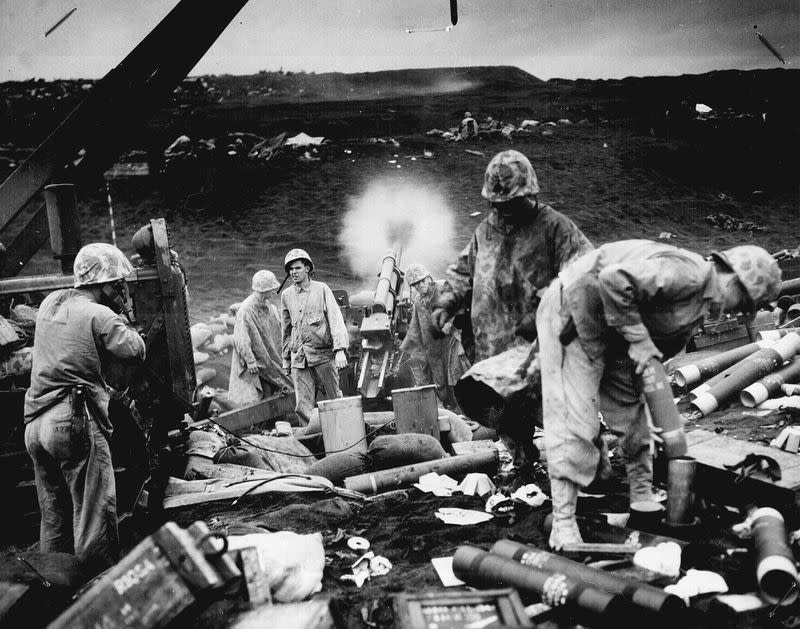 U.S. Marines with the Fourth Division fire on enemy positions from the black sands of an Iwo Jima beach