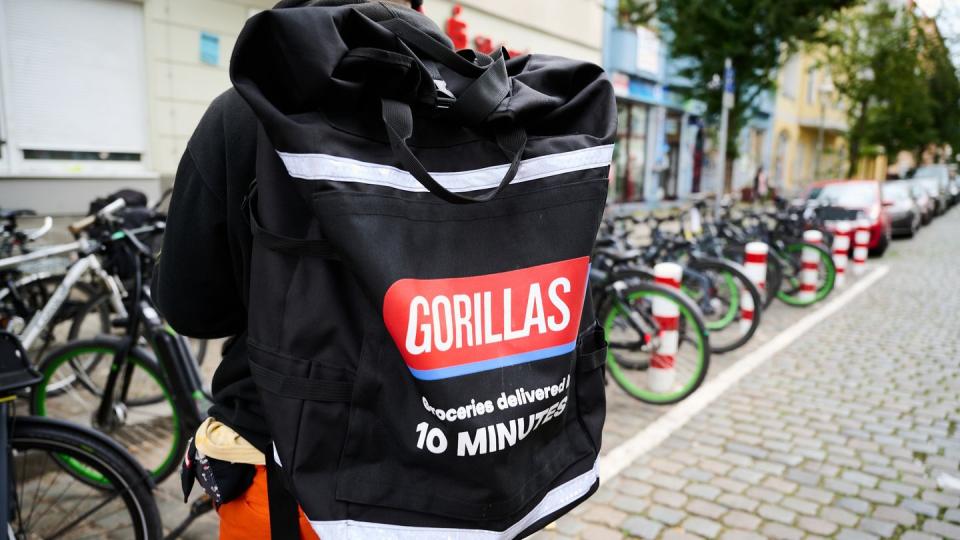 Ein Beschäftigter des Lieferdienstes Gorillas trägt einen Rucksack und steht vor den Fahrrädern.