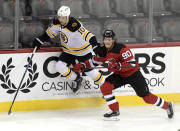 Boston Bruins left wing Anders Bjork (10) attempts to get by New Jersey Devils center Jesper Boqvist (90) during the first period of an NHL hockey game Saturday, Jan. 16, 2021, in Newark, N.J. (AP Photo/Bill Kostroun)