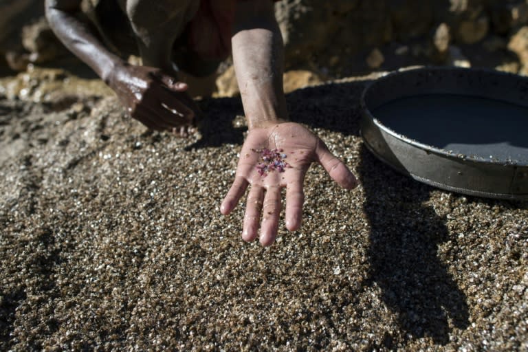 A miner shows pieces of ruby and jade at a mine in Mogok, Myanmar