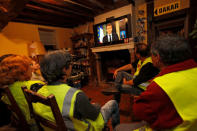 Protesters wearing yellow vests watch French President Emmanuel Macron who addresses the nation about the "yellow vests" crisis on a TV screen in a house in Gaillon, France, December 10, 2018. REUTERS/Philippe Wojazer