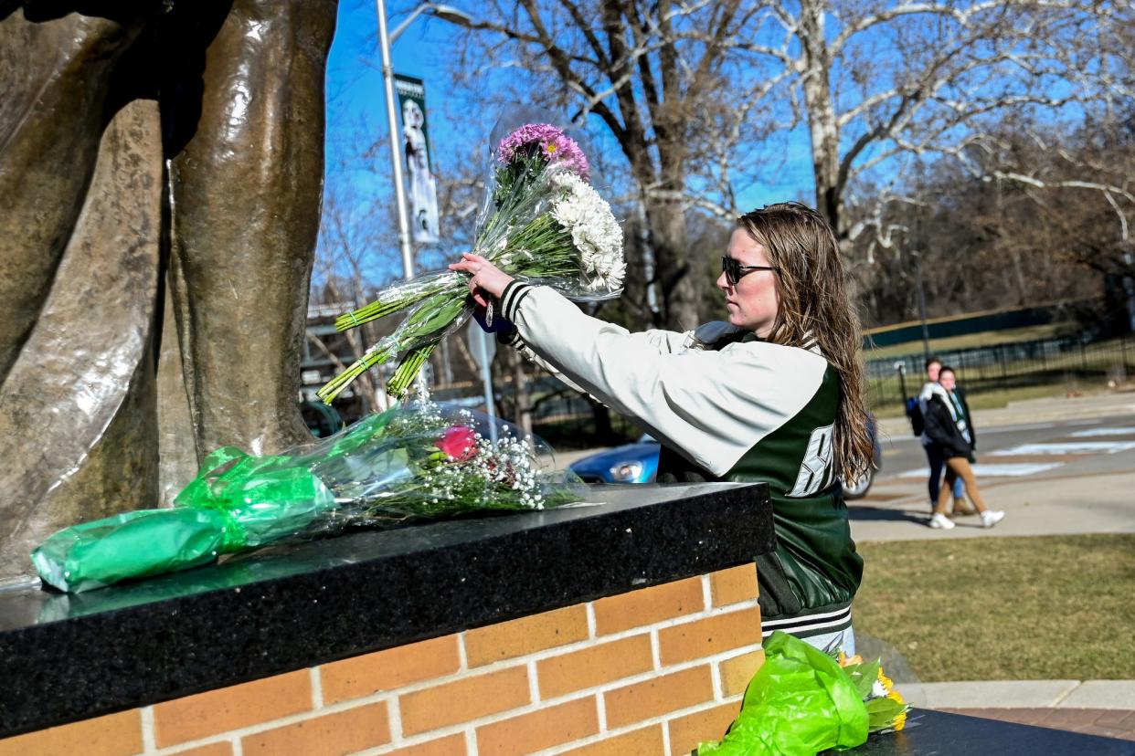 Michigan State senior Julia Wallace places three bouquets of flowers at the feet of the Sparty statue on Tuesday, Feb. 14, 2023, on the MSU campus in East Lansing. Wallace brought a bouquet each for the three killed in the shooting on campus.