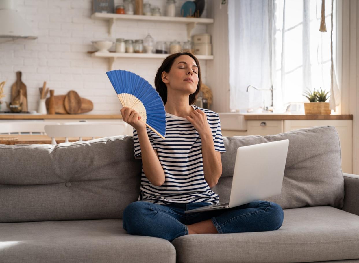 woman sitting on sofa with a laptop in a hot room