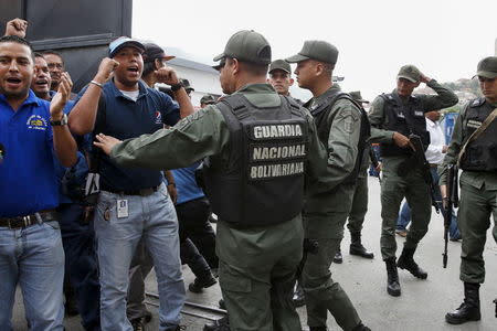 Venezuelan National Guards talk to Empresas Polar workers while they shout at the gate of a facility used by the company as a distribution center, during the occupation of its installations by government representatives in Caracas July 30, 2015. REUTERS/Carlos Garcia Rawlins
