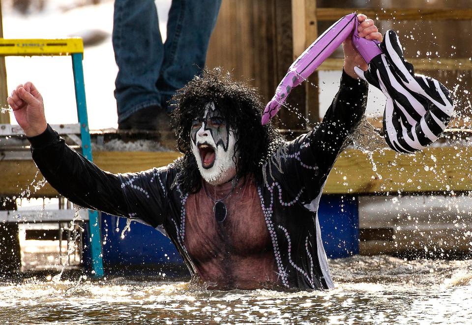 Dan Fahey, of Thornville, dressed as one of the members of Kiss, along with his friends, as the Kiss Plunger Team, comes out of the frigid waters with his hands raised holding an inflatable guitar after jumping off the boat docks at Buckeye Lake Winery during the Buckeye Lake Polar Plunge 2022 in in Thornville, Ohio. A record number of jumpers, over 130 people, cave out to participate in the annual event.