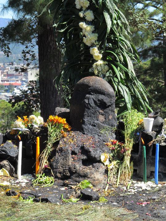 This February 2013 photo shows a shrine for a Mayan deity surrounded by offerings and candles near Chichicastenango, in Guatemala's western highlands. Chichicastenango is also famed for an expansive local crafts market. (AP Photo/Amir Bibawy)