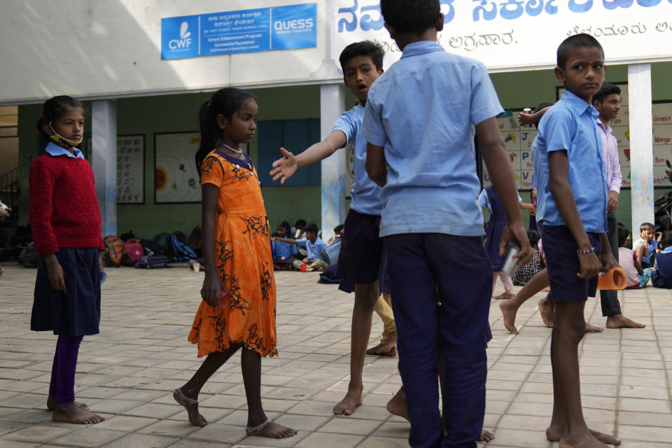 Jerifa Islam, second left, lines up with other students to receive free milk distributed at a government school near her home in Bengaluru, India, Wednesday, July 20, 2022. A flood in 2019 in the Darrang district of India's Assam state started Jerifa, her brother Raju and their parents on a journey that led the family from their Himalayan village to the poor neighborhood. (AP Photo/Aijaz Rahi)