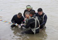 A woman is helped after being pulled out by divers from a sunken ship in Jianli, Hubei province, China, June 2, 2015. REUTERS/cnsphoto