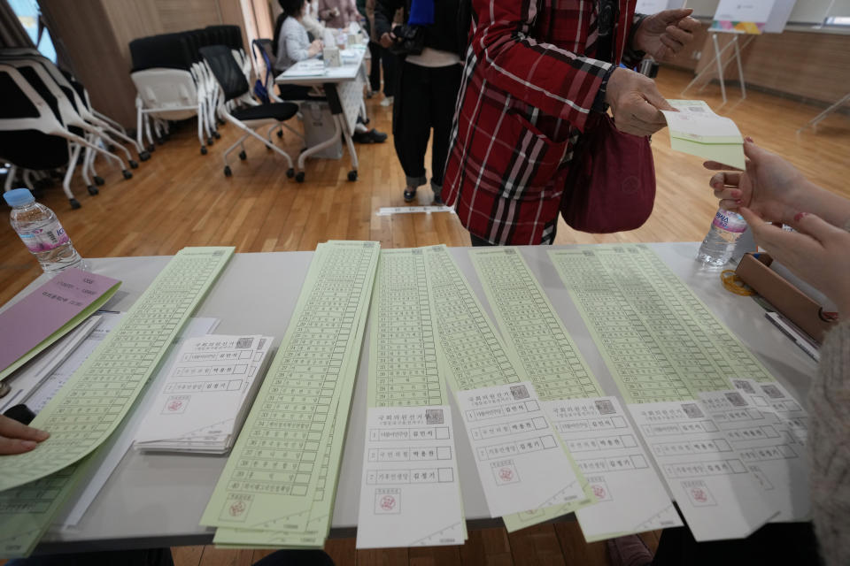 A voter receives ballots from an election official for the parliamentary election at a polling station in Seoul, South Korea, Wednesday, April 10, 2024. South Korean President Yoon Suk Yeol faces a crucial referendum Wednesday in a parliamentary election that could determine whether he becomes a lame duck or enjoys a mandate to pursue key policies for his remaining three years in office. (AP Photo/Ahn Young-joon)