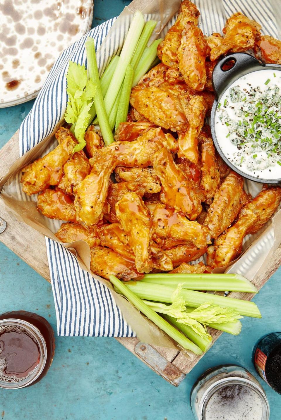 a plate of buffalo wings with dip and celery