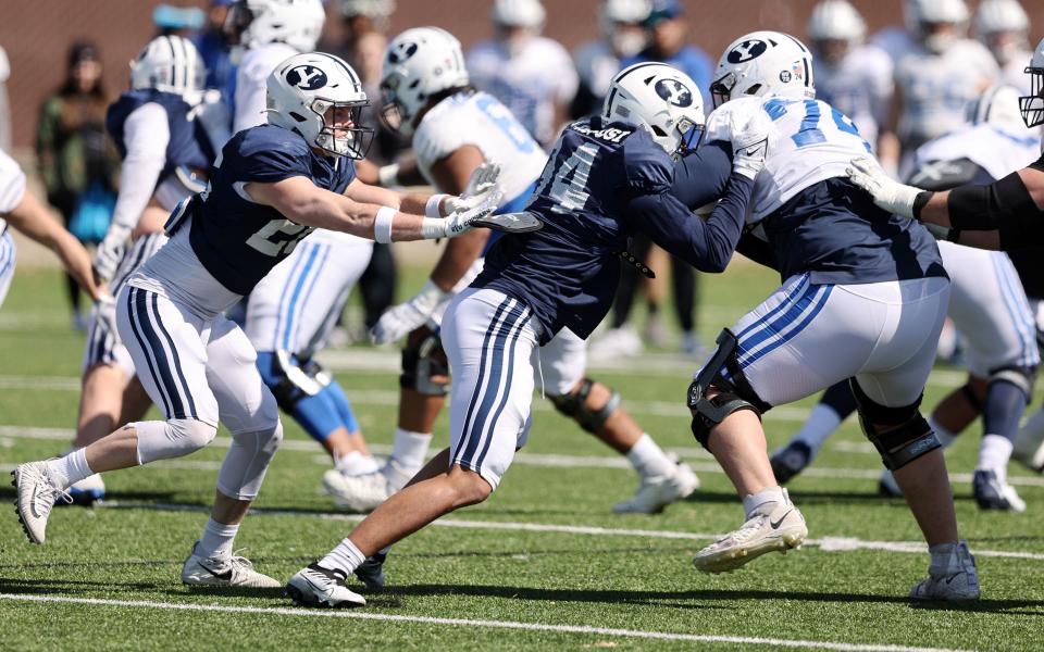 Safety Ethan Slade and linebacker Kaika Kaufusi battle offensive lineman Trevin Ostler as practices in Provo on Friday, March 17, 2023.
